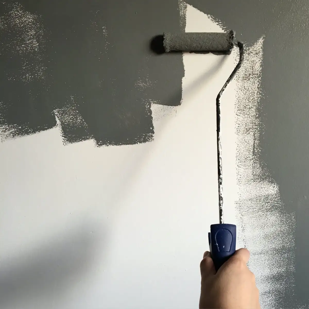 Painter rolling gray paint on an interior wall